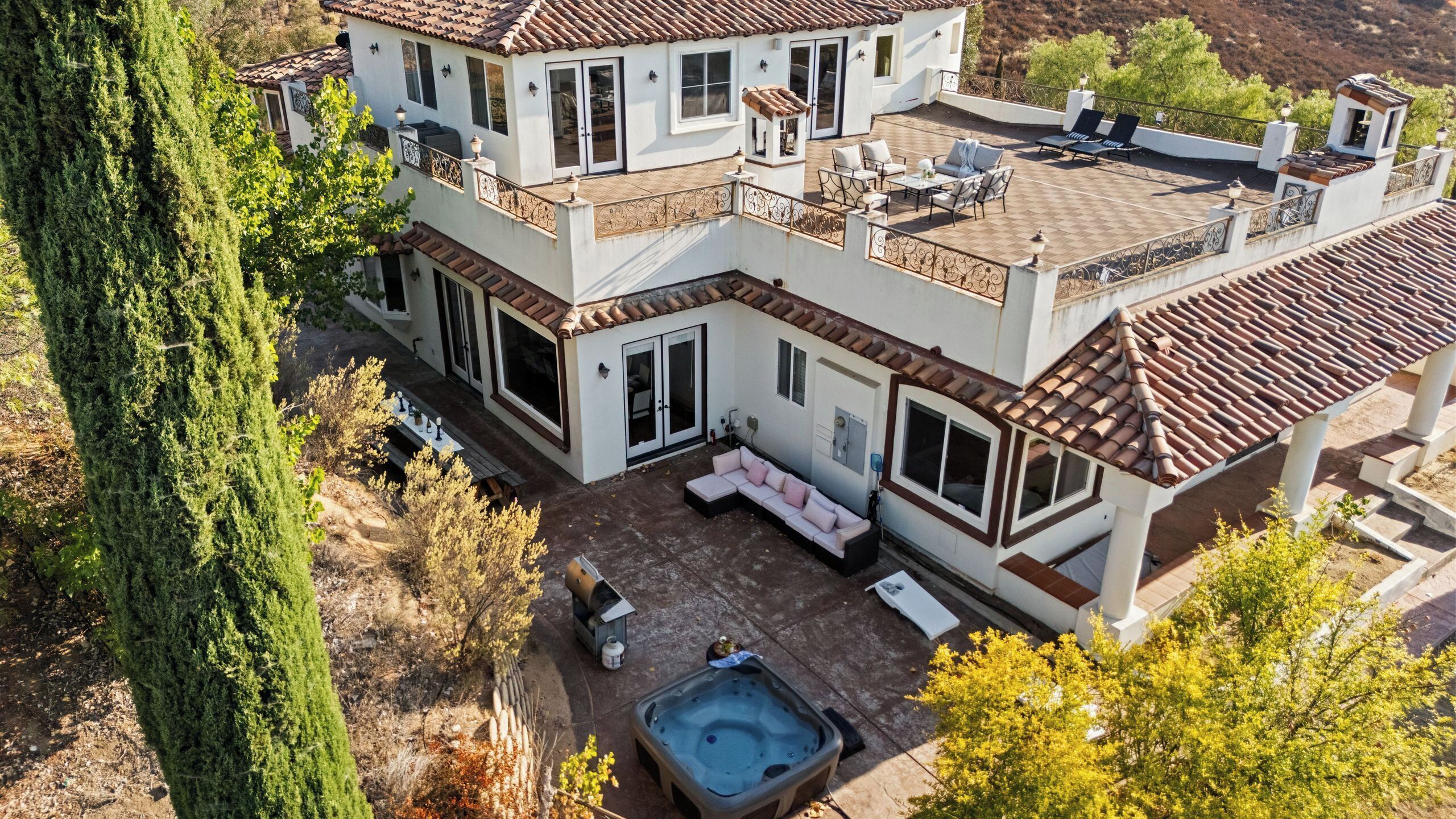A multi-story house with a patio, outdoor seating, and a hot tub.