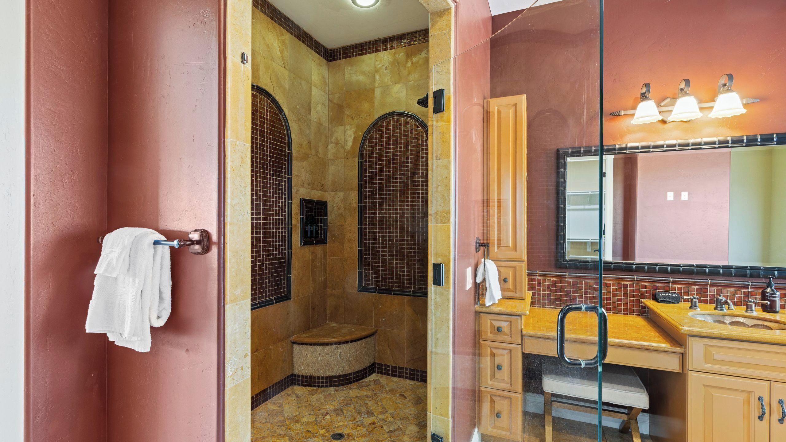 A bathroom with a shower, vanity, and a mirror.