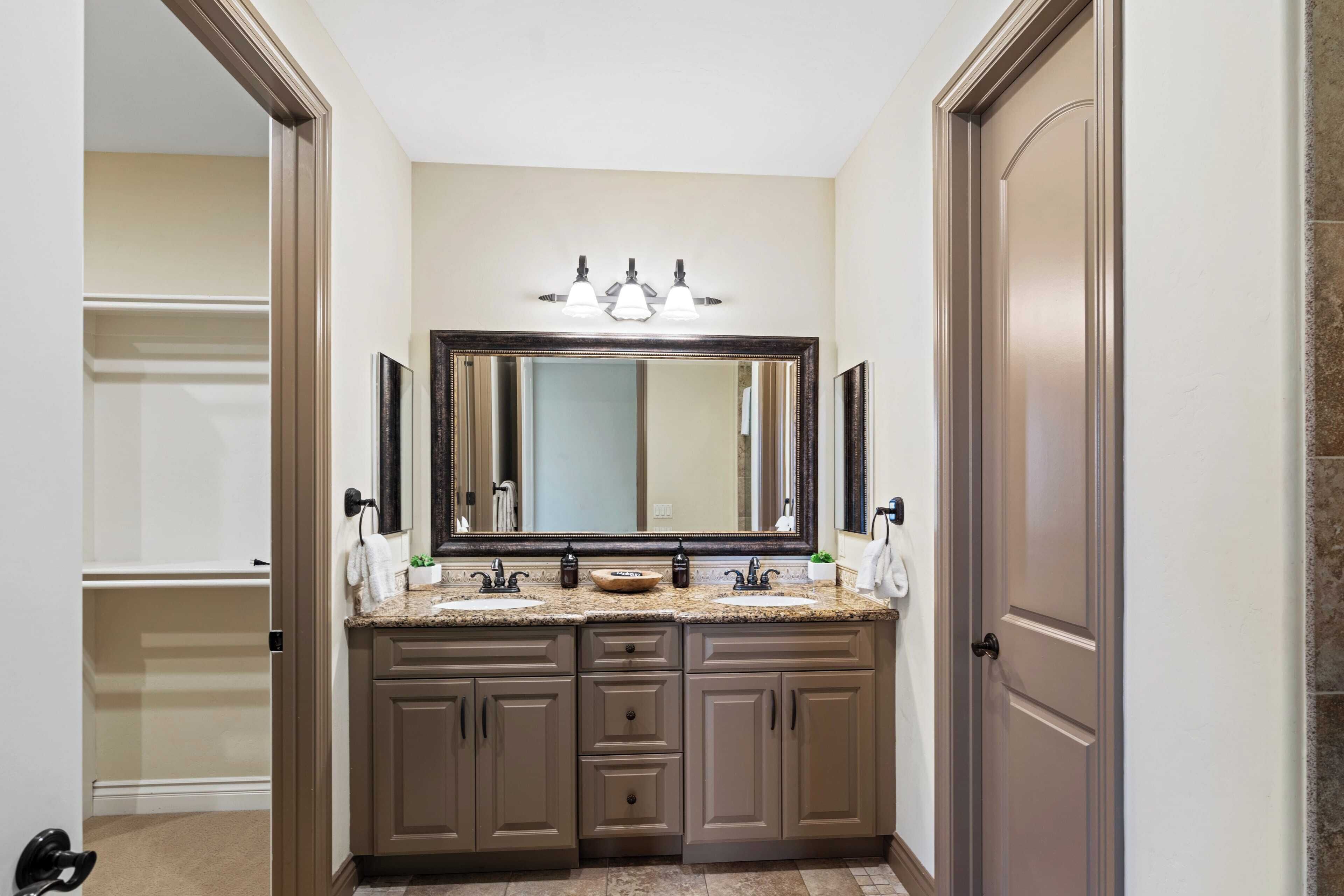 Une salle de bain avec deux lavabos, un grand miroir et un meuble-lavabo avec des placards.