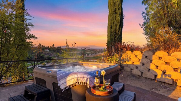 Un jacuzzi con vistas al paisaje, mobiliario exterior y un muro de piedra.