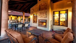 An outdoor patio area with a stone fireplace, seating, and tables. - Owl's Nest by Avantstay Infinity Pool w/ Incredible Views (Temecula)