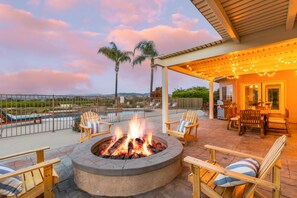 Una terraza en la azotea con una chimenea, mobiliario exterior y vistas a las montañas.