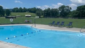 A swimming pool with blue water, a concrete deck, and several lounge chairs.