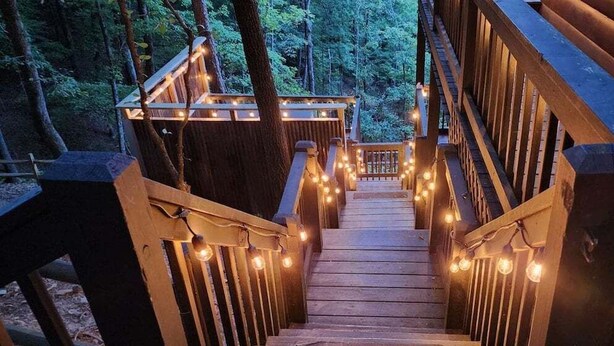 A wooden staircase with string lights leading to a deck surrounded by trees. - Big Sky Lodge - stunning view (Blue Ridge)
