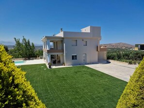 A modern two-story house with a swimming pool, surrounded by well-maintained lawns and trees. - Blue Sky Villa in Crete (heraklion)