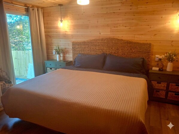 Un dormitorio con paneles de madera, una cama grande, mesitas de noche y vistas al exterior.