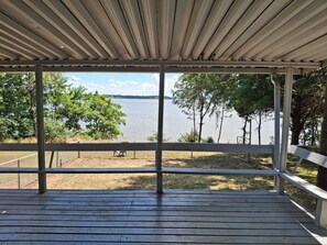 Un espace extérieur abrité offrant une vue sur un lac et des arbres.