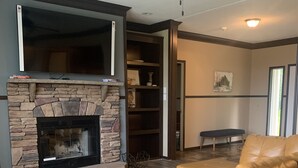 A living room with a stone fireplace, leather sofa, and a ceiling fan.