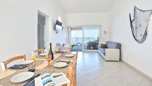 Un coin repas avec une table dressée pour quatre personnes, un canapé et une vue sur l’extérieur.