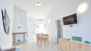 Un salon moderne comprenant un coin repas, un téléviseur fixé au mur et une cheminée.