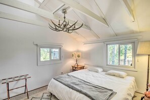 Un dormitorio con cama, candelabro, dos ventanas, lámpara y un tendedero.