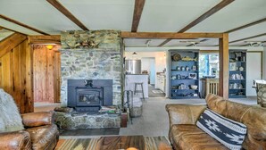 Una sala de estar acogedora con chimenea de piedra, sofás de cuero y una estantería.