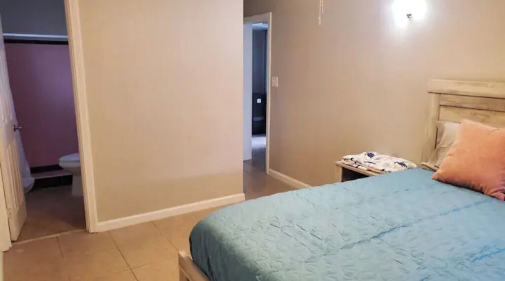 Ein Schlafzimmer mit einem Bett, einem Nachttisch und einer Tür zu einem Badezimmer.