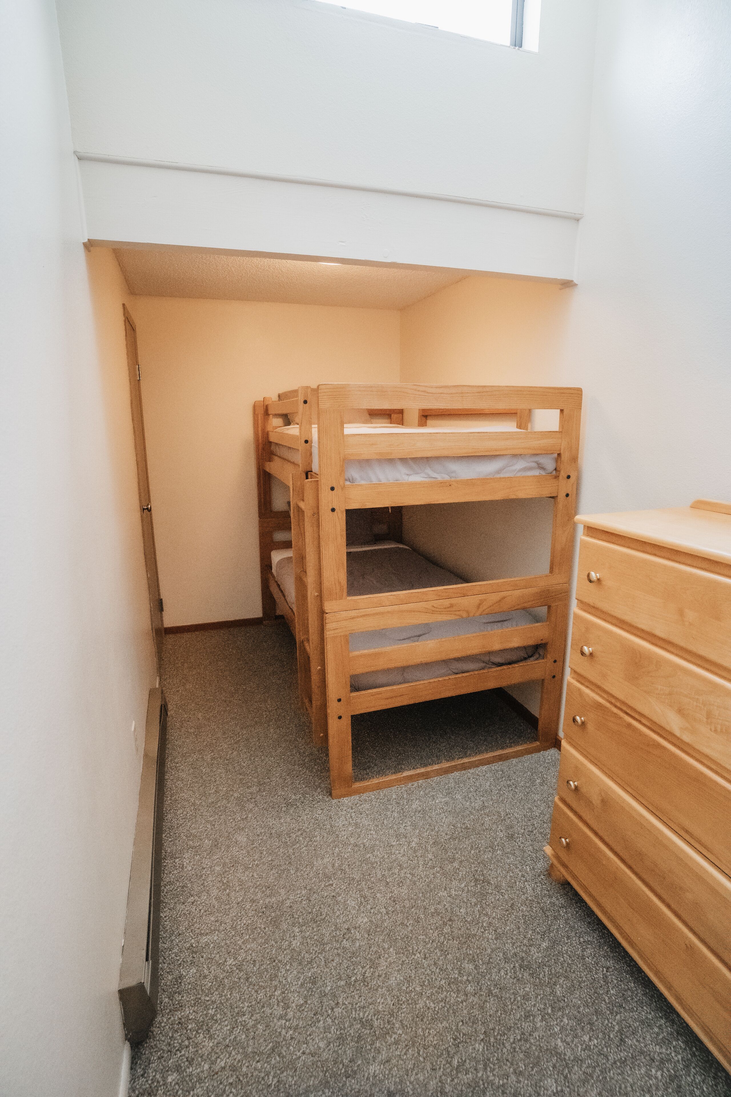 Ein Stockbett in einem Raum mit einem hölzernen Schminktisch und einem Fenster.