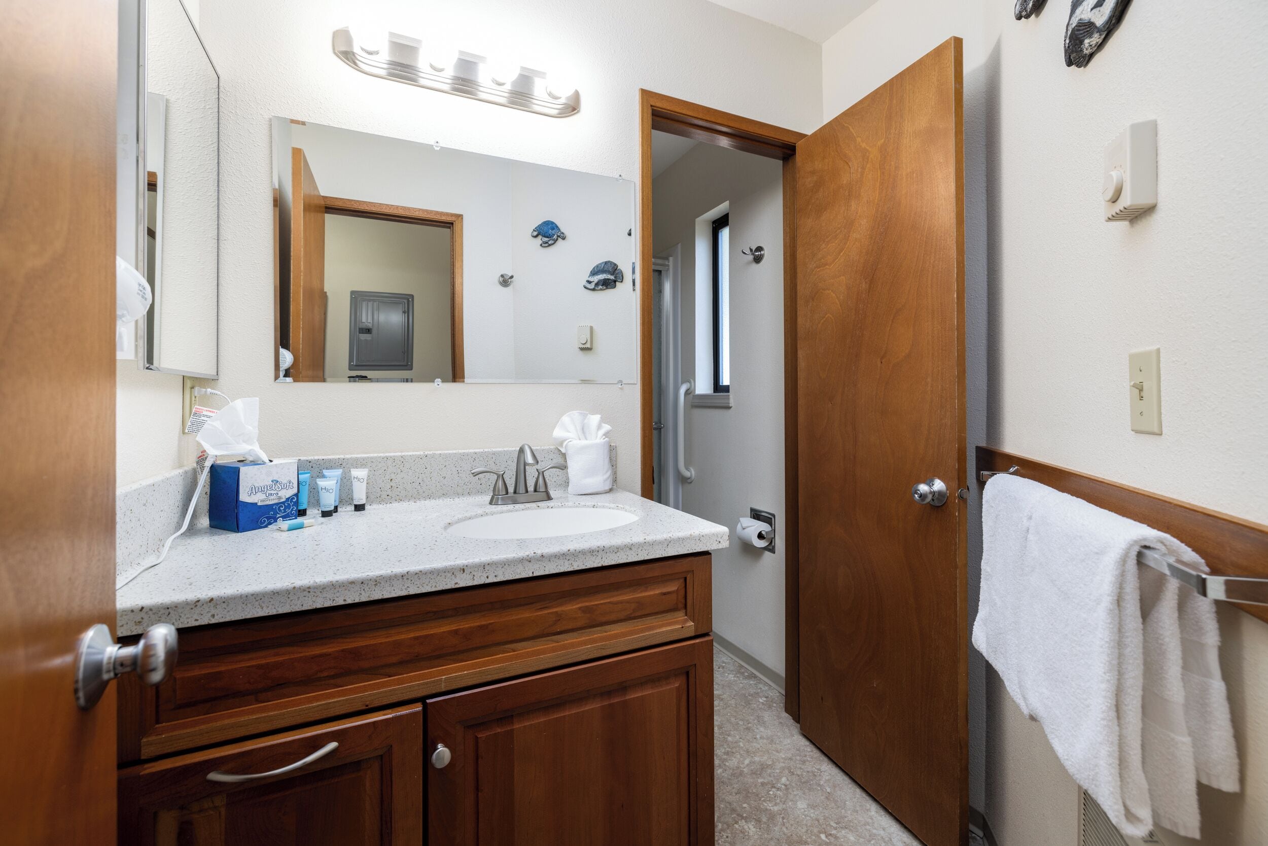 A bathroom with a wooden vanity, a sink, and a mirror. There is a towel rack with a towel hanging on it.