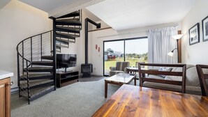 Una sala de estar con una mesa de centro de madera, un sofá, un televisor y una chimenea.