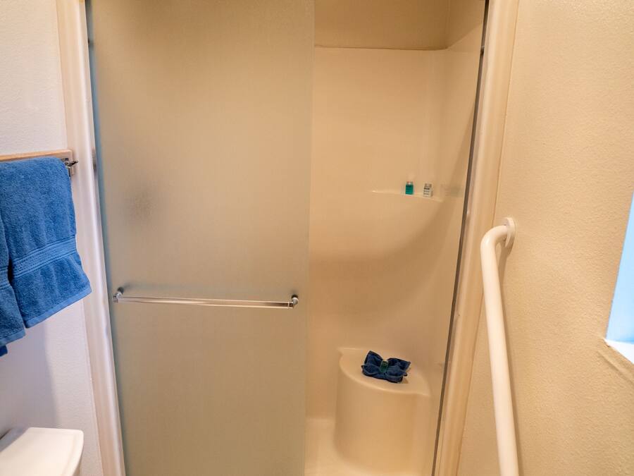 Een kleine, afgesloten douchecel met een glazen deur, een toilet en een handdoekhouder.