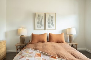A bedroom with a large bed, two bedside lamps, and two framed abstract artworks on the wall. - Wallace BNB (Pinedale)