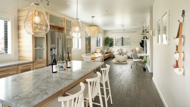 A modern kitchen with a marble countertop, wooden cabinets, and pendant lighting.