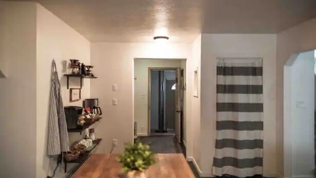 A hallway with a wooden table, a potted plant, and a striped curtain. - The Farmhouse - Clean, comfortable, and affordable! (Fairbanks)