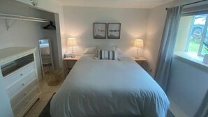 A bedroom with a bed, bedside tables, a dresser, and a window with curtains. - The Farmhouse - Clean, comfortable, and affordable! (Fairbanks)