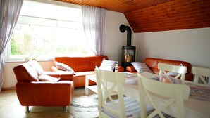 Una sala de estar acogedora con techo de madera, un sofá, una mesa y una chimenea.