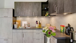 Eine moderne Küche mit grauen Schränken, Edelstahlgeräten und einem Blumenstrauß auf der Arbeitsplatte.