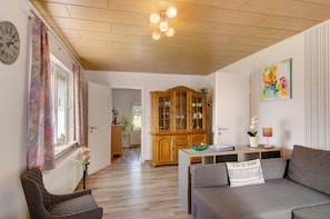 A living room with a wooden ceiling, a sofa, a cabinet, and a dining table.