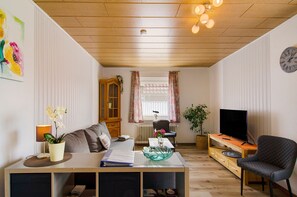 A living room with a sofa, a coffee table, a TV stand, a lamp, and a plant.