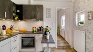 Eine moderne Küche mit dunklen Schränken, einem eingebauten Backofen und einer Arbeitsplatte mit verschiedenen Küchenutensilien.
