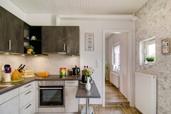 A modern kitchen with dark cabinets, a built-in oven, and a countertop with various kitchen items.
