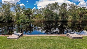 Un parc paisible au bord d’un lac, offrant une vue dégagée sur l’eau, et entouré d’une végétation luxuriante et d’arbres.