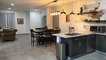 A modern kitchen with dark cabinetry, a granite countertop, a stainless steel sink, and a built-in microwave.