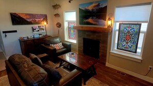 A living room with a fireplace, leather sofa, coffee table, and artwork on the walls. - the Sunset House - modern comfort with spectacular views (Leadville)
