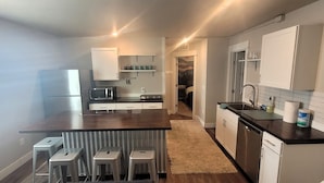 A modern kitchen with a central island, stainless steel appliances, and a view into the adjacent bedroom. - the Sunset House - modern comfort with spectacular views (Leadville)