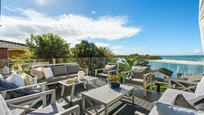 A deck with outdoor furniture, a view of the sea, and a pool.