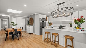 A modern kitchen with a central island, stainless steel appliances, and a pendant light fixture.