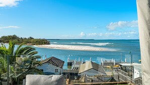 A beachfront property with a clear view of the sea, a sandy beach, and a forested area.
