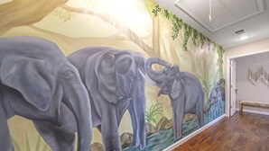 A hallway with a mural of elephants and a wooden floor.