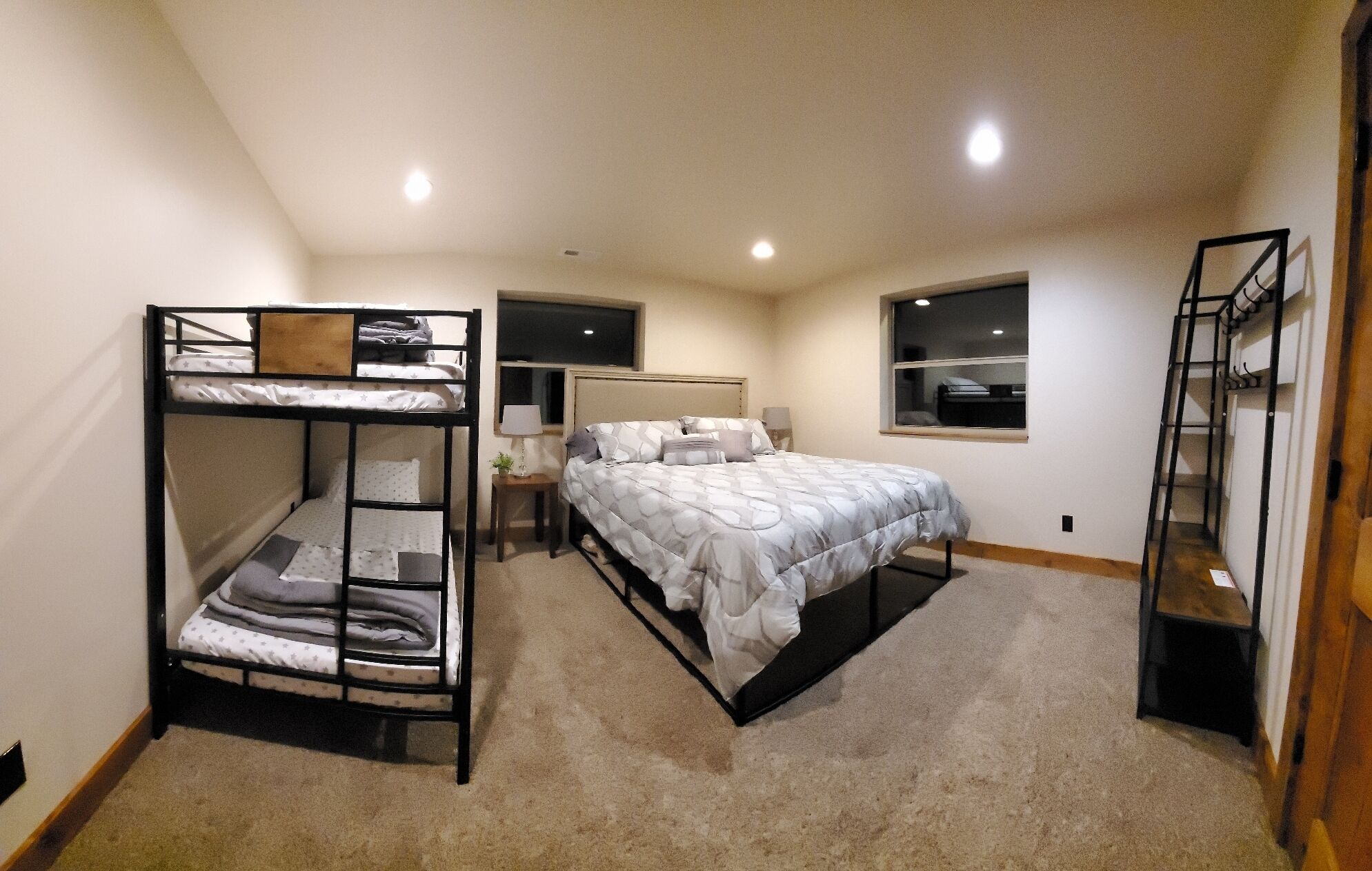 Une chambre avec des lits superposés, un lit simple, une table de chevet, une lampe et une fenêtre.