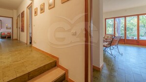 Un pasillo amplio con una escalera que lleva a un balcón con vista a árboles.