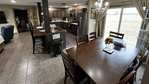 A spacious kitchen with modern appliances, a dining area with a chandelier, and a view of the outdoors.