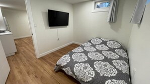 Quarto com cama, televisão na parede e janela com cortina.