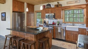 A spacious kitchen with wooden cabinets, stainless steel appliances, and a large island with stools. - Posey Meadow Ranch - Wilson Mesa, 70 Acres with Views upon Views (Placerville)