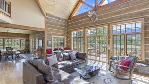 A log cabin interior with a large leather sofa, a glass coffee table, and a deer head mounted on the wall. - Posey Meadow Ranch - Wilson Mesa, 70 Acres with Views upon Views (Placerville)