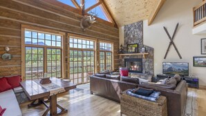 A spacious living room with a stone fireplace, large windows, and a cozy seating area. - Posey Meadow Ranch - Wilson Mesa, 70 Acres with Views upon Views (Placerville)