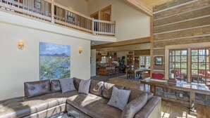 A spacious living area with a leather sofa, a painting, and a dining area with a stone countertop. - Posey Meadow Ranch - Wilson Mesa, 70 Acres with Views upon Views (Placerville)