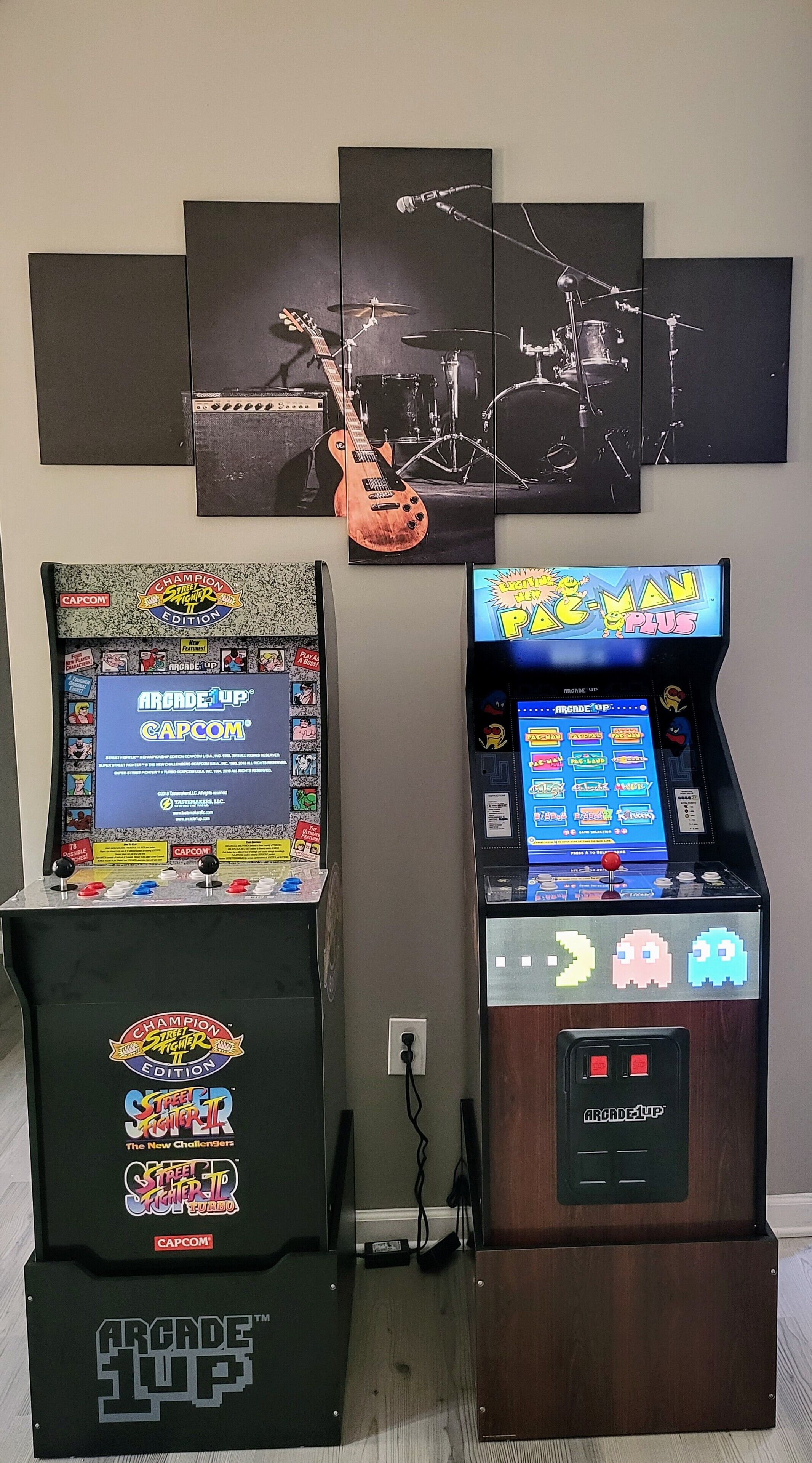 Two arcade machines, one with a 'Street Fighter II' label and another with a 'Pac-Man' label, against a wall with a 'Champion Street Fighter II' poster.