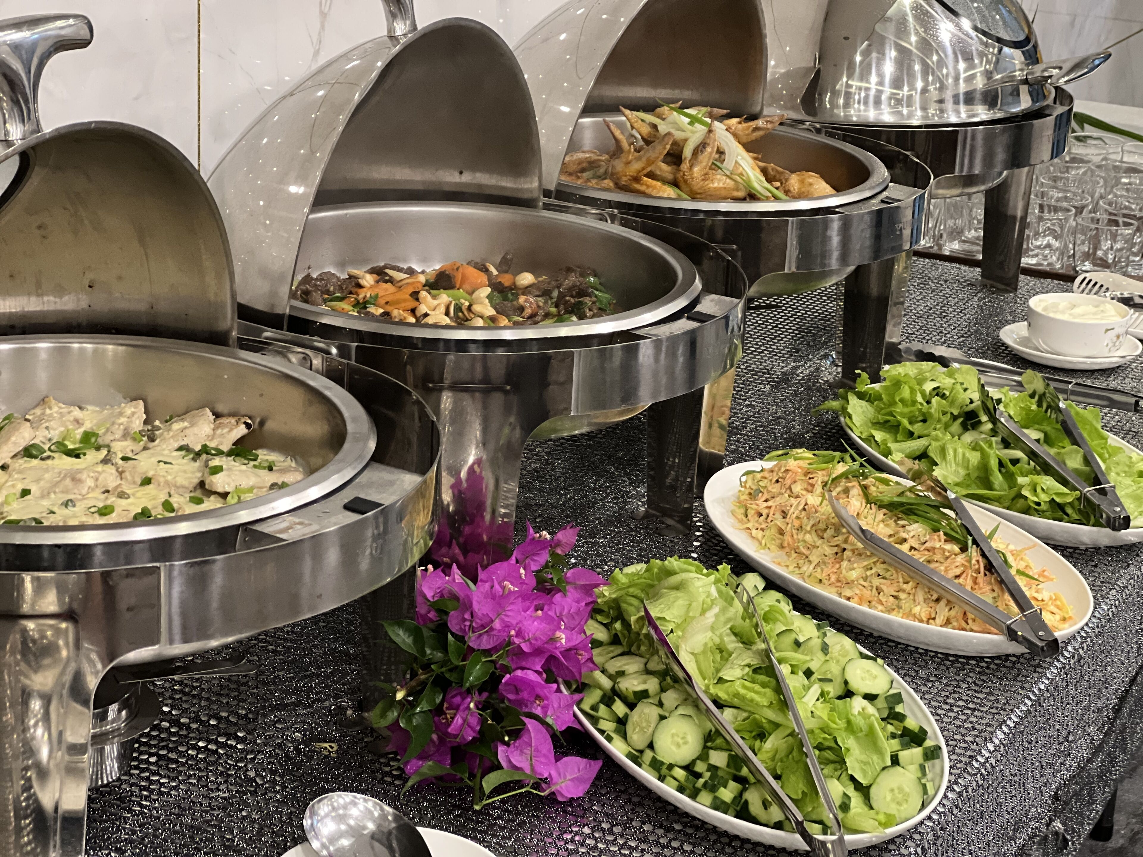 Un buffet proposant une variété de plats, notamment des salades, des légumes et des viandes.