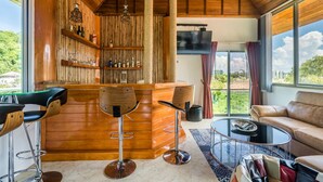 A modern living room with a wooden bar area, two bar stools, a sofa, and a coffee table. - Exclusive Villa Stan with Top Amenities (Kamala)